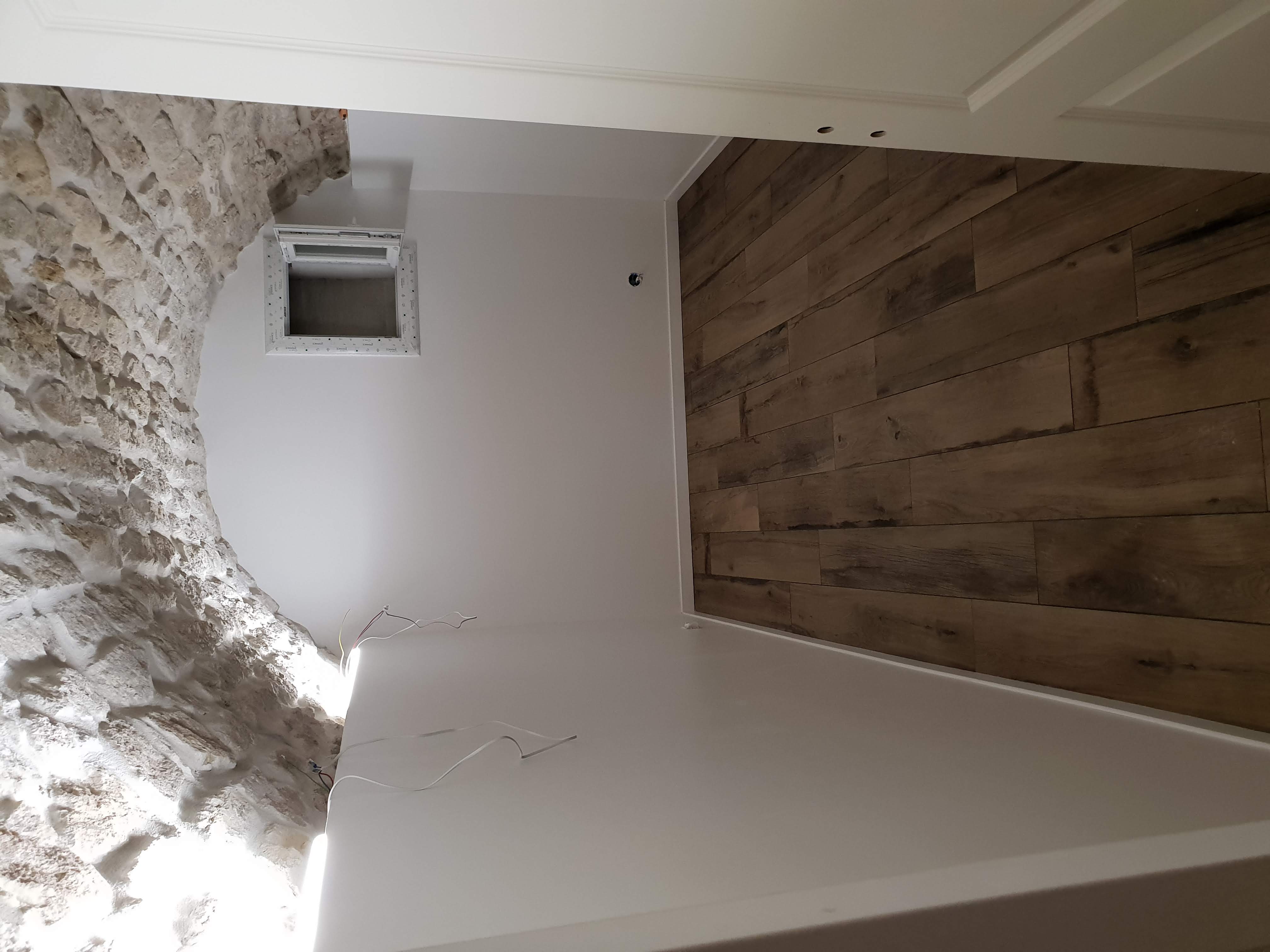 Pièce aménagée en sous-sol, lumineuse avec fenêtre, sol parquet, sous voûte en pierre