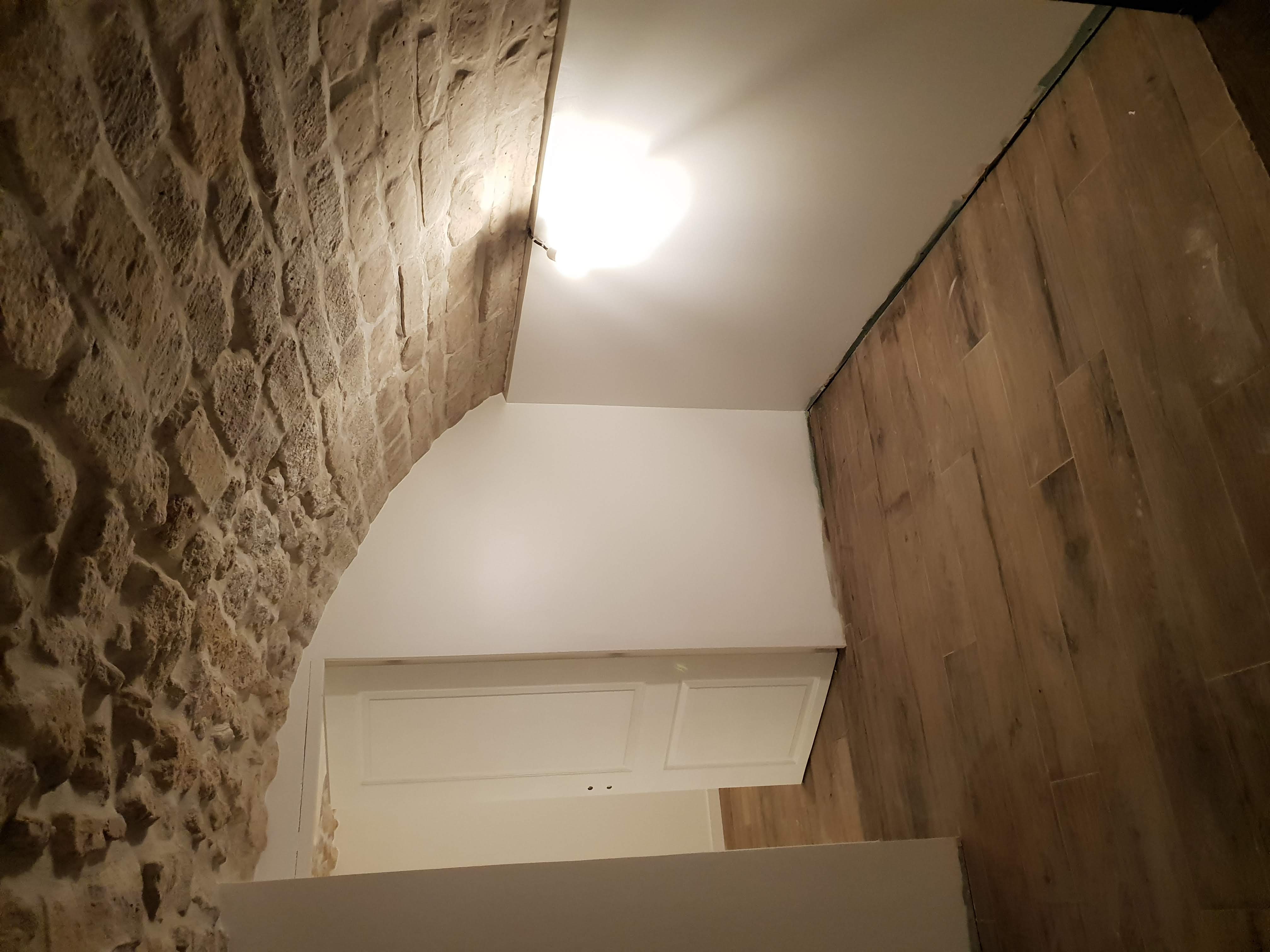 Cave voûtée parisienne aménagée en pièce de vie : voûte en pierre conservée, murs blancs, sol posé