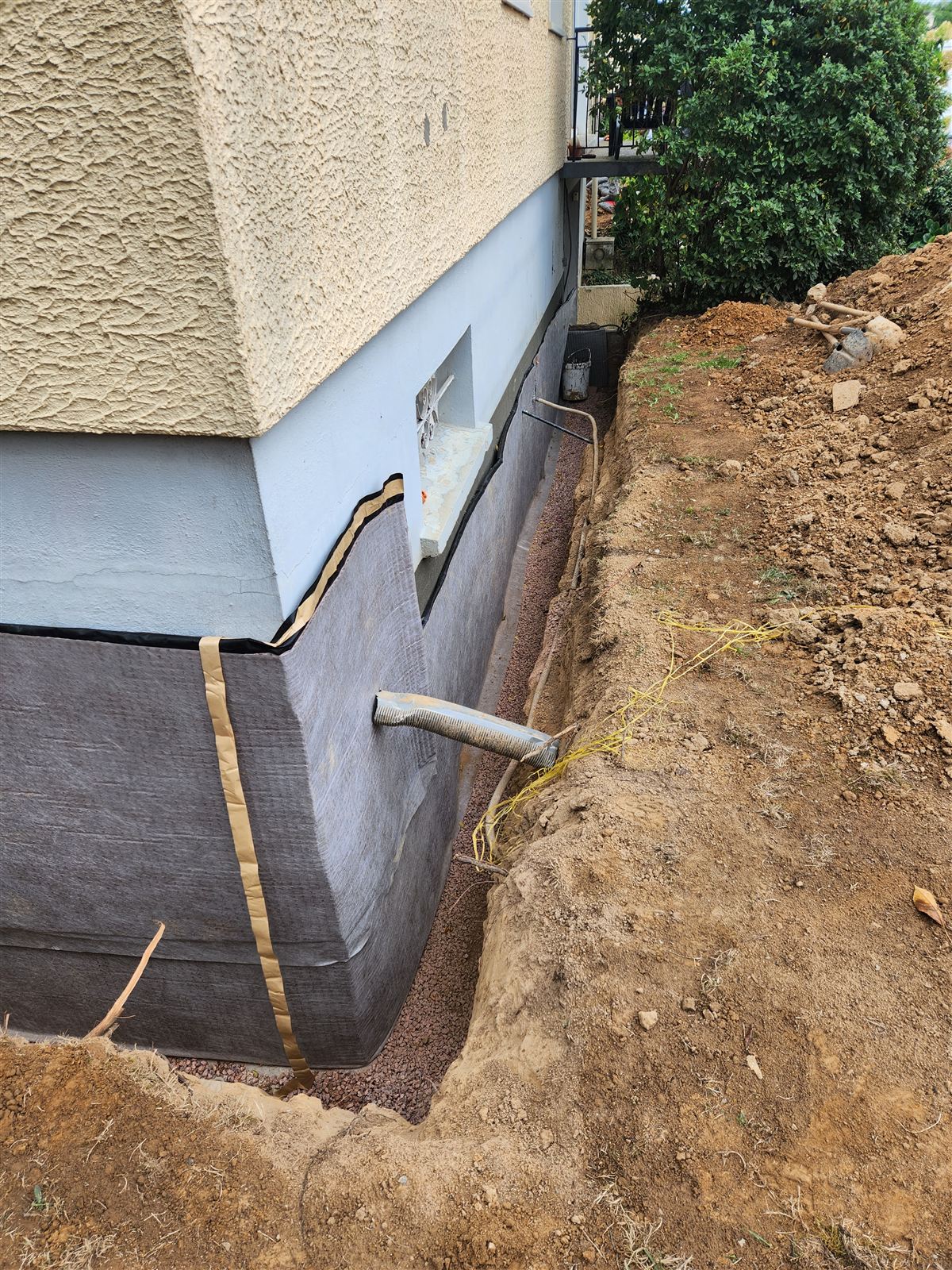 Drain périphérique et gravier posés dans la tranchée le long de la fondation