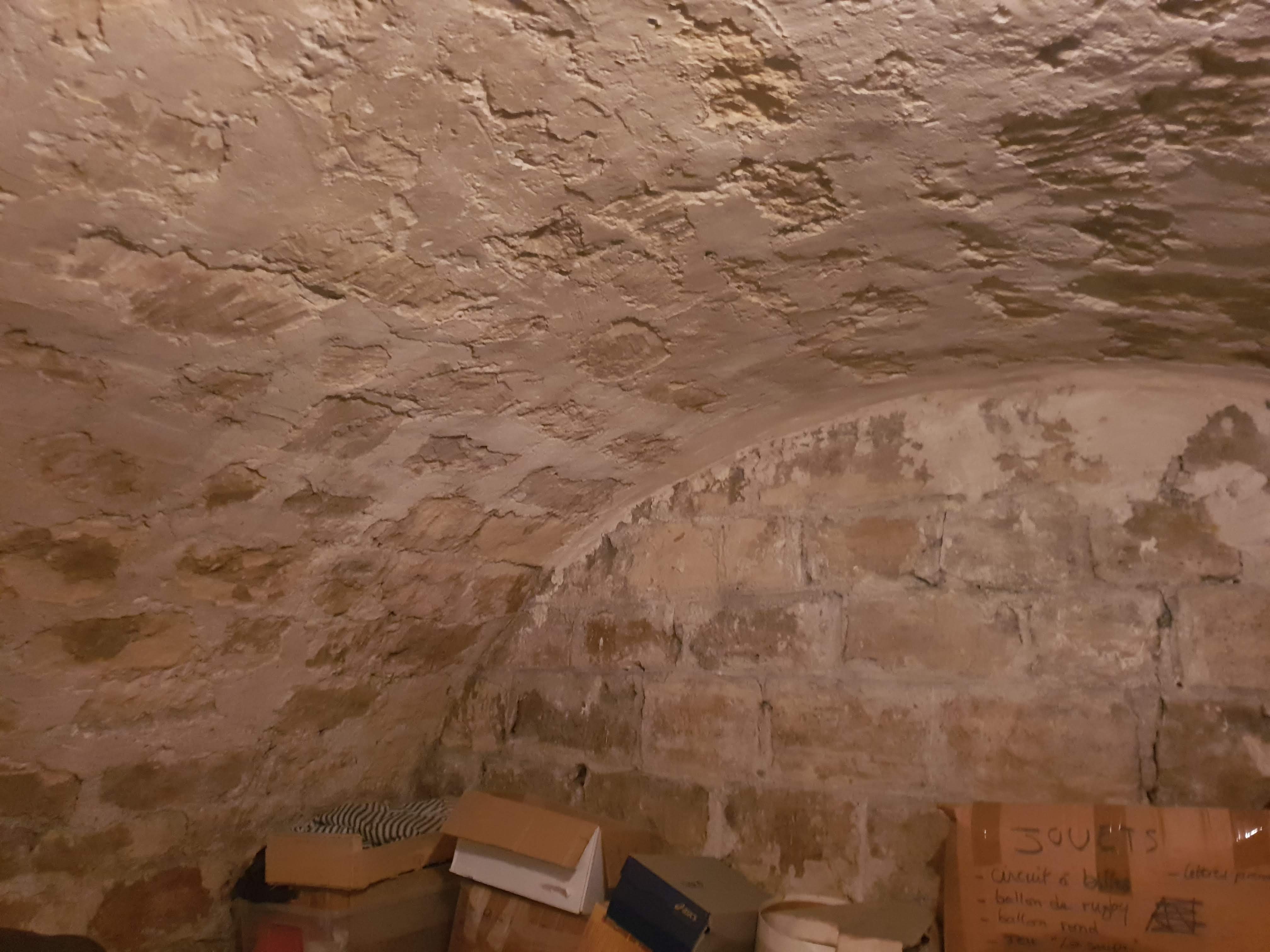 Cave voûtée humide aux Lilas avant travaux : enduit dégradé, pierre encrassée, utilisée en débarras