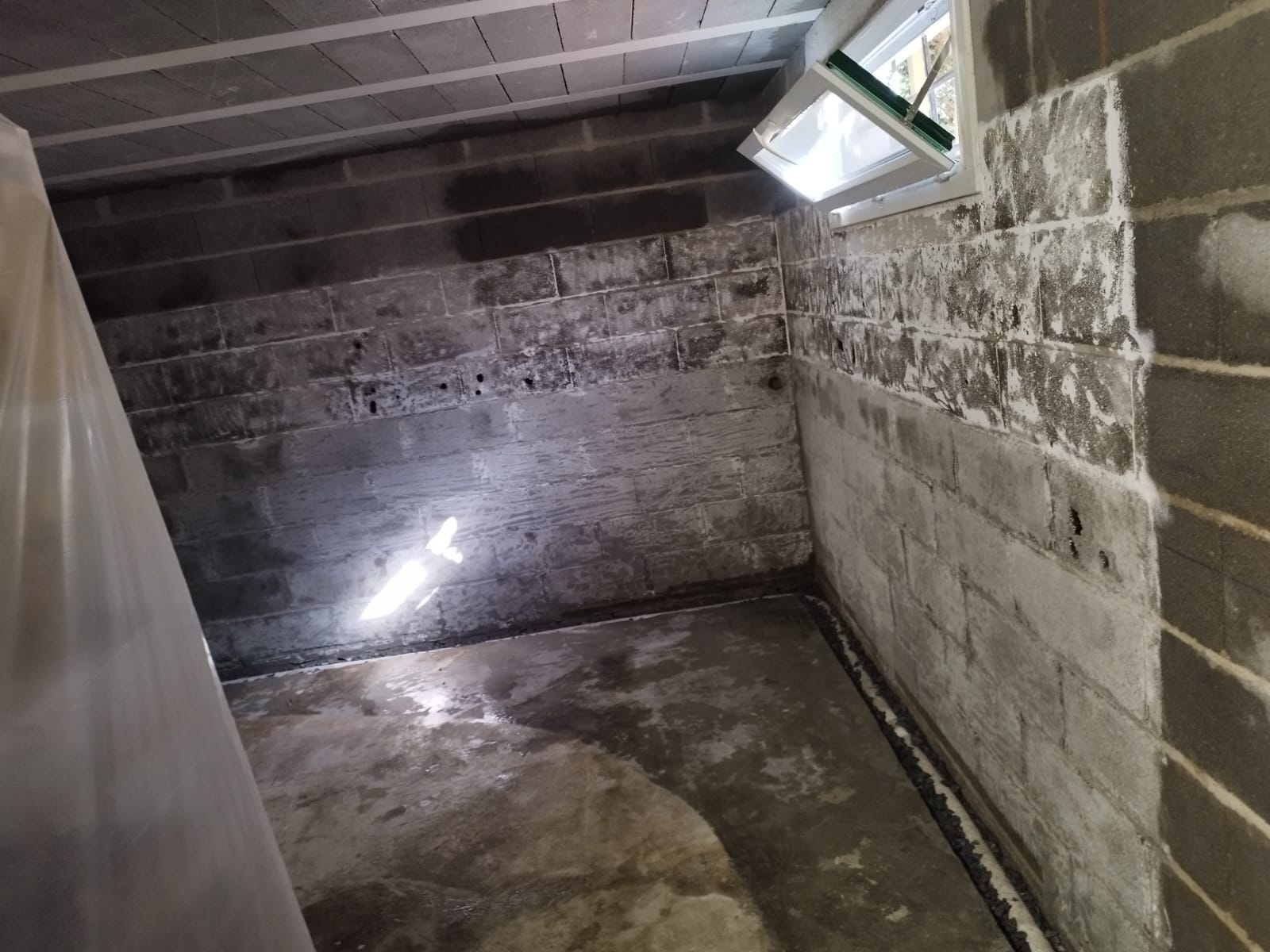 Sous-sol à Olivet : un mur cuvelé (mortier hydrofuge) et un drainage en gravier en pied de mur, à côté d'un mur encore brut