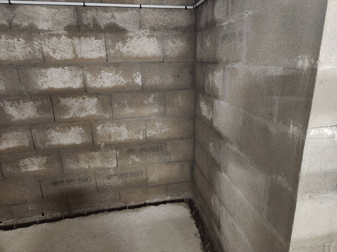 Sous-sol en parpaings à Presles-en-Brie avant travaux : murs bruts et tranchée de drainage ouverte au pied des murs