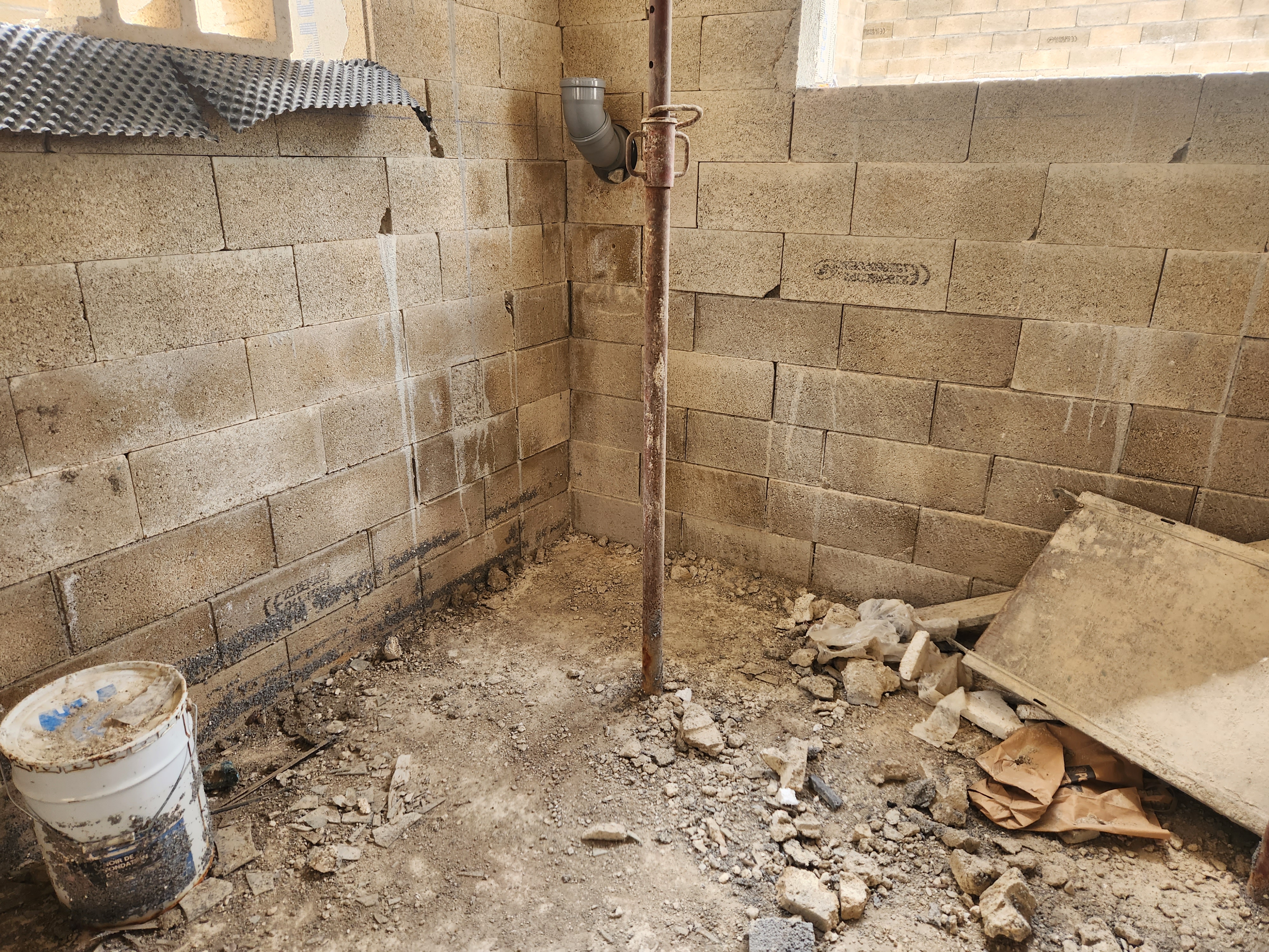 Sous-sol en parpaings à Sevran avant travaux : murs bruts exposés à l'humidité, gravats au sol